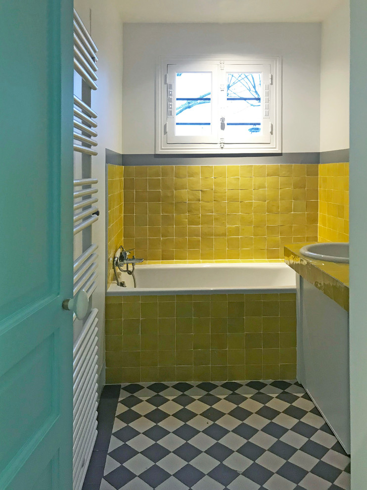 Идея дизайна: маленькая детская ванная комната в стиле фьюжн с полновстраиваемой ванной, душем в нише, желтой плиткой, керамической плиткой, желтыми стенами, полом из цементной плитки, столешницей из плитки, серым полом и желтой столешницей для на участке и в саду