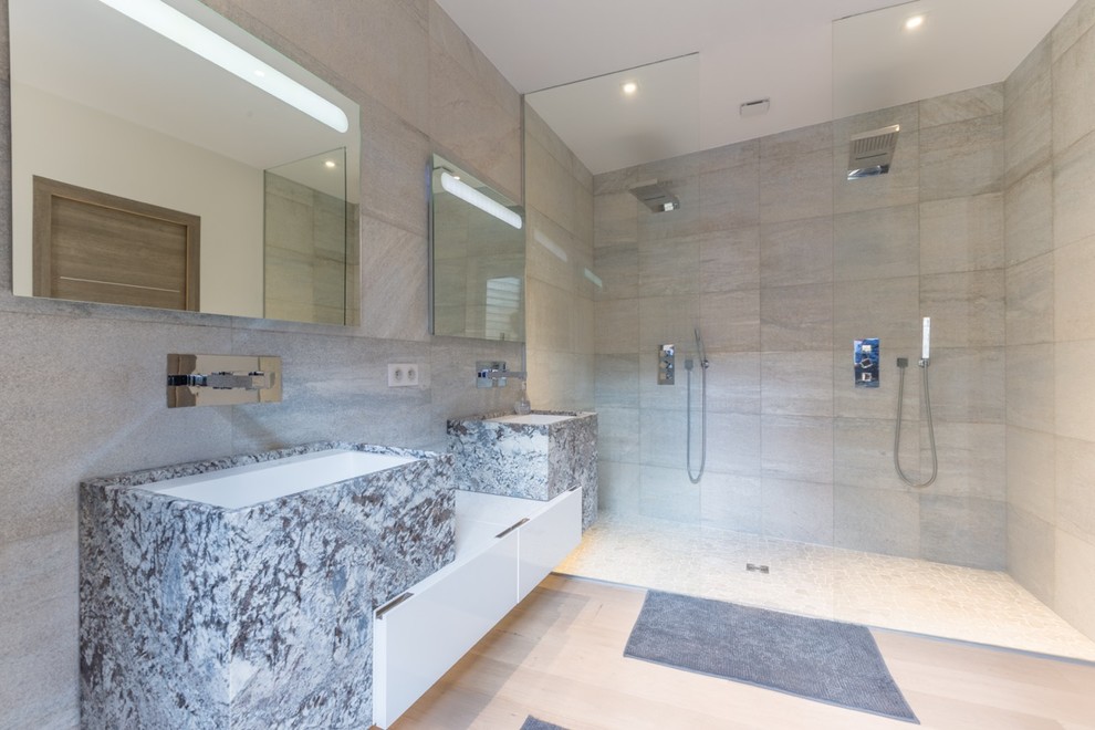 На фото: главная ванная комната среднего размера в стиле модернизм с мраморной столешницей, двойным душем, светлым паркетным полом, серой плиткой, серыми стенами и подвесной раковиной