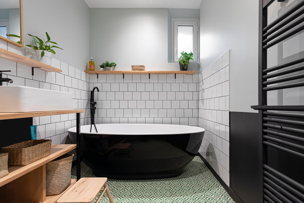 Modernes Badezimmer mit freistehender Badewanne, weißen Fliesen, grauer Wandfarbe, Aufsatzwaschbecken, Waschtisch aus Holz, grünem Boden, brauner Waschtischplatte und Einzelwaschbecken in Lyon