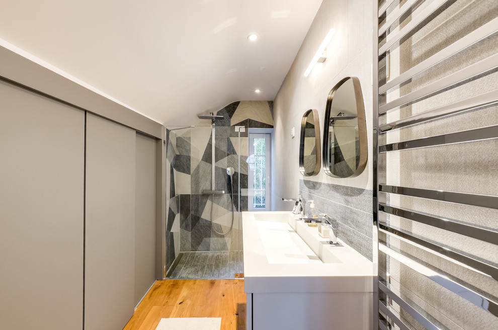 Mittelgroßes Modernes Duschbad mit Kassettenfronten, grauen Schränken, bodengleicher Dusche, blauen Fliesen, hellem Holzboden und Aufsatzwaschbecken in Paris