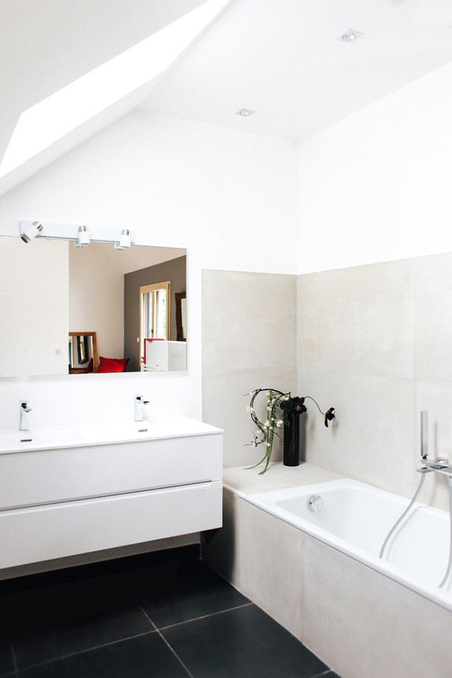 Idee per una stanza da bagno design di medie dimensioni con vasca sottopiano, piastrelle beige, piastrelle di cemento, pareti bianche, pavimento in ardesia, lavabo a consolle, top in vetro e ante bianche