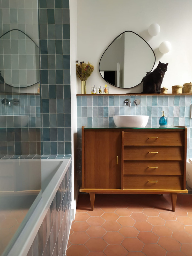 Пример оригинального дизайна: ванная комната среднего размера в современном стиле с фасадами цвета дерева среднего тона, ванной в нише, душем над ванной, синей плиткой, белыми стенами, полом из терракотовой плитки, душевой кабиной, настольной раковиной, стеклянной столешницей, оранжевым полом, открытым душем, синей столешницей, тумбой под одну раковину, напольной тумбой и плоскими фасадами