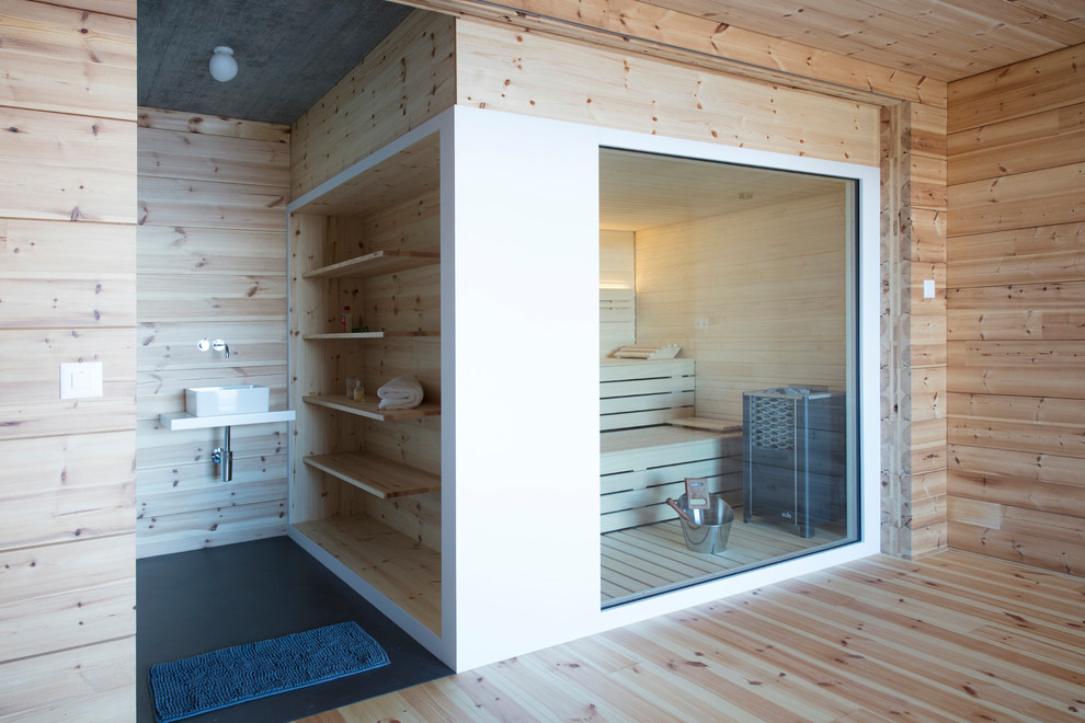 Cette photo montre un sauna montagne avec un mur marron, un sol en bois brun, une vasque, un sol marron et un plan de toilette blanc.