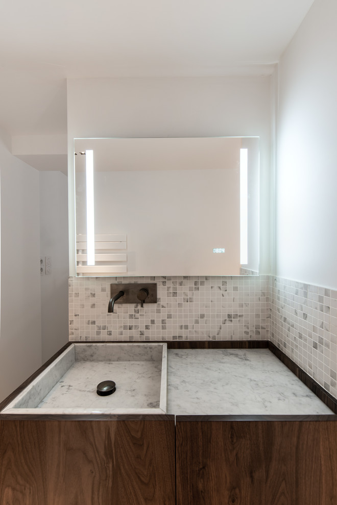 Idée de décoration pour une salle d'eau design de taille moyenne avec un placard à porte affleurante, des portes de placard marrons, une douche à l'italienne, un carrelage blanc, du carrelage en marbre, un mur blanc, sol en béton ciré, un lavabo encastré, un plan de toilette en marbre, un sol gris, une cabine de douche à porte battante et un plan de toilette blanc.