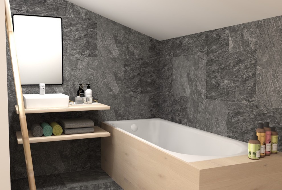 Exemple d'une petite salle de bain principale montagne avec une baignoire encastrée, un carrelage noir, du carrelage en ardoise, un mur gris, un plan vasque, un plan de toilette en bois et un sol noir.