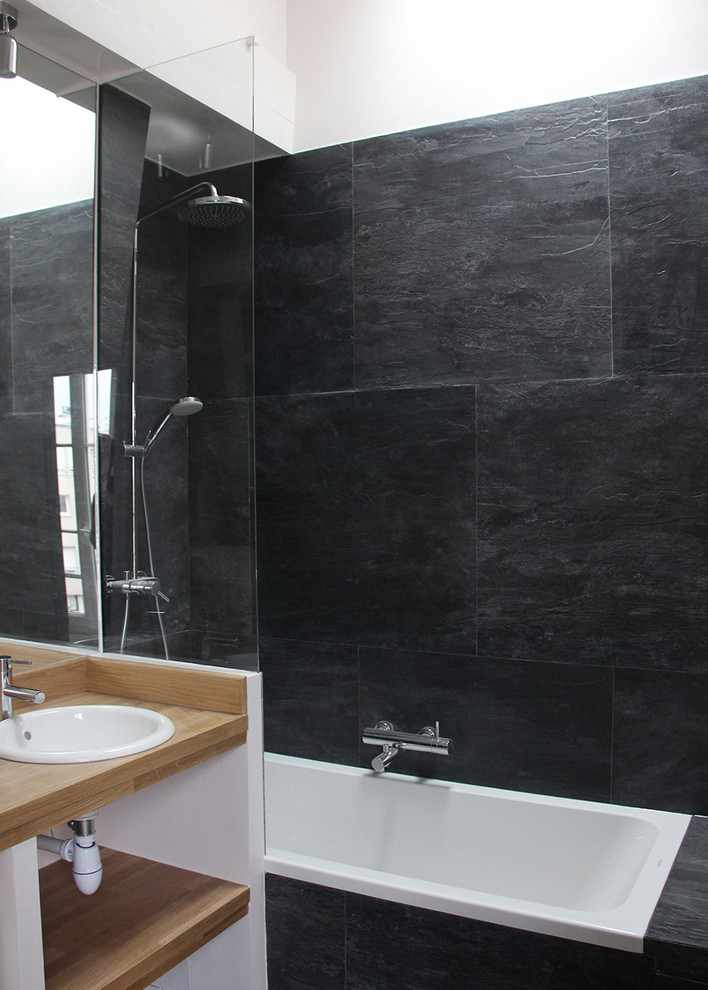 Photo of a small modern ensuite bathroom in Paris with a built-in sink, wooden worktops, an alcove bath, a shower/bath combination, black tiles, slate tiles and brown worktops.