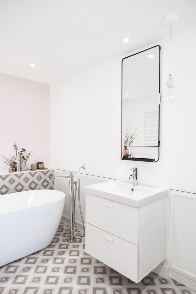 На фото: главная ванная комната среднего размера в современном стиле с плоскими фасадами, белыми фасадами, отдельно стоящей ванной, разноцветной плиткой, розовыми стенами, разноцветным полом, инсталляцией, керамической плиткой, полом из керамической плитки, консольной раковиной, столешницей из искусственного камня, открытым душем, белой столешницей, тумбой под одну раковину и подвесной тумбой