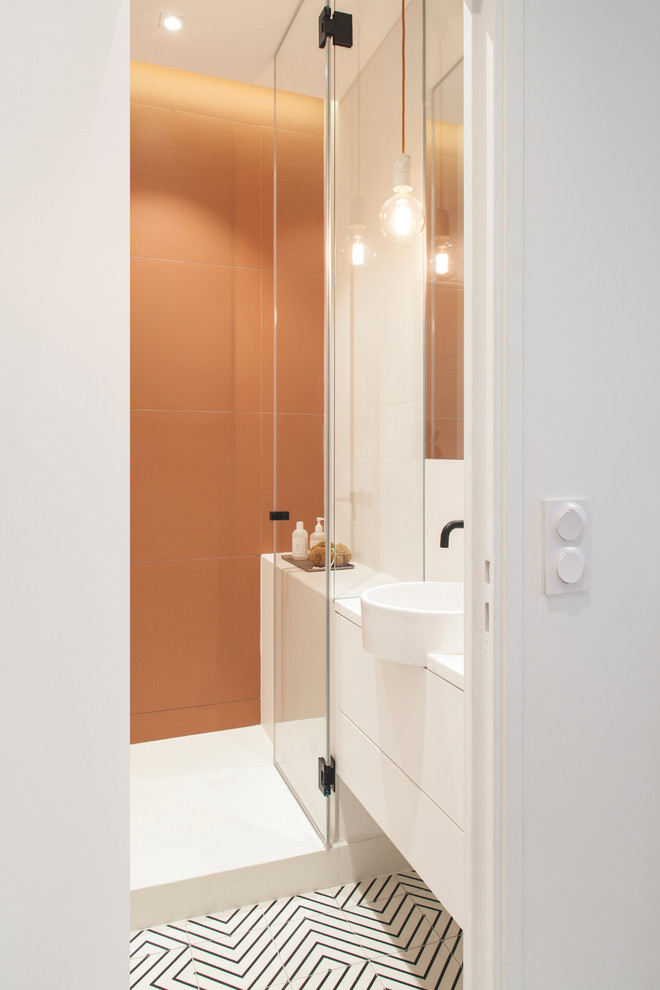 Exempel på ett mellanstort skandinaviskt vit vitt badrum med dusch, med släta luckor, vita skåp, en öppen dusch, en vägghängd toalettstol, orange kakel, keramikplattor, vita väggar, cementgolv, ett fristående handfat, bänkskiva i akrylsten, flerfärgat golv och dusch med gångjärnsdörr