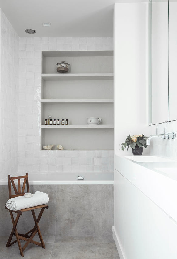 Klassisk inredning av ett en-suite badrum, med ett konsol handfat, luckor med profilerade fronter, ett fristående badkar, stenhäll och vita väggar