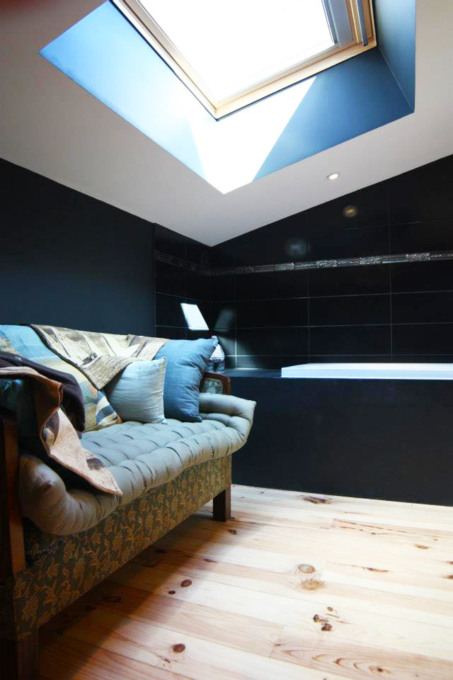 Inredning av ett modernt mellanstort en-suite badrum, med öppna hyllor, svarta skåp, en dusch i en alkov, svart kakel, svarta väggar, ljust trägolv, ett nedsänkt handfat, bänkskiva i betong och brunt golv