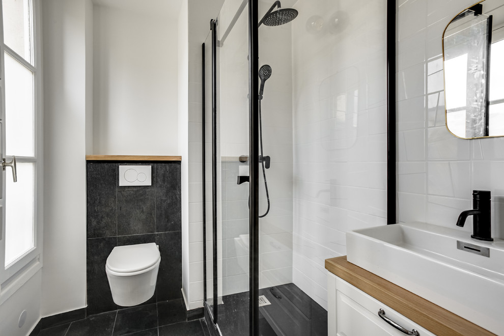 Idéer för att renovera ett mellanstort funkis vit vitt en-suite badrum, med en hörndusch, en vägghängd toalettstol, keramikplattor, svarta väggar, skiffergolv, ett nedsänkt handfat, träbänkskiva och dusch med gångjärnsdörr
