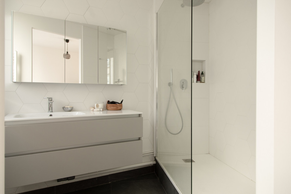 Modern inredning av ett mellanstort vit vitt en-suite badrum, med släta luckor, grå skåp, en kantlös dusch, vit kakel, keramikplattor, vita väggar, klinkergolv i keramik, ett konsol handfat, bänkskiva i akrylsten, svart golv och med dusch som är öppen