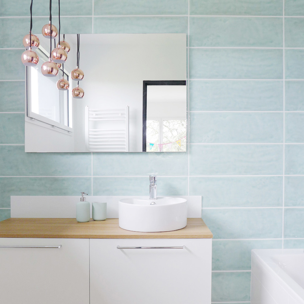 Diseño de cuarto de baño contemporáneo de tamaño medio con armarios con paneles lisos, puertas de armario blancas, baldosas y/o azulejos azules, paredes azules, lavabo sobreencimera, encimera de madera y encimeras marrones