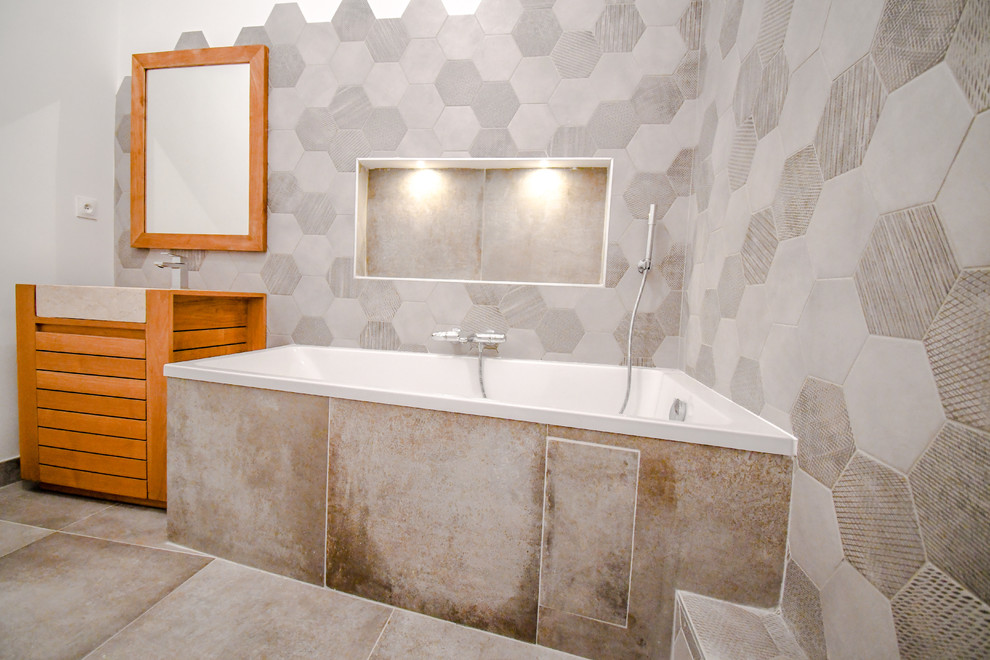 Пример оригинального дизайна: ванная комната среднего размера в стиле лофт с полновстраиваемой ванной, открытым душем, инсталляцией, серой плиткой, серыми стенами, полом из керамической плитки, душевой кабиной, настольной раковиной, столешницей из искусственного камня, серым полом и бежевой столешницей