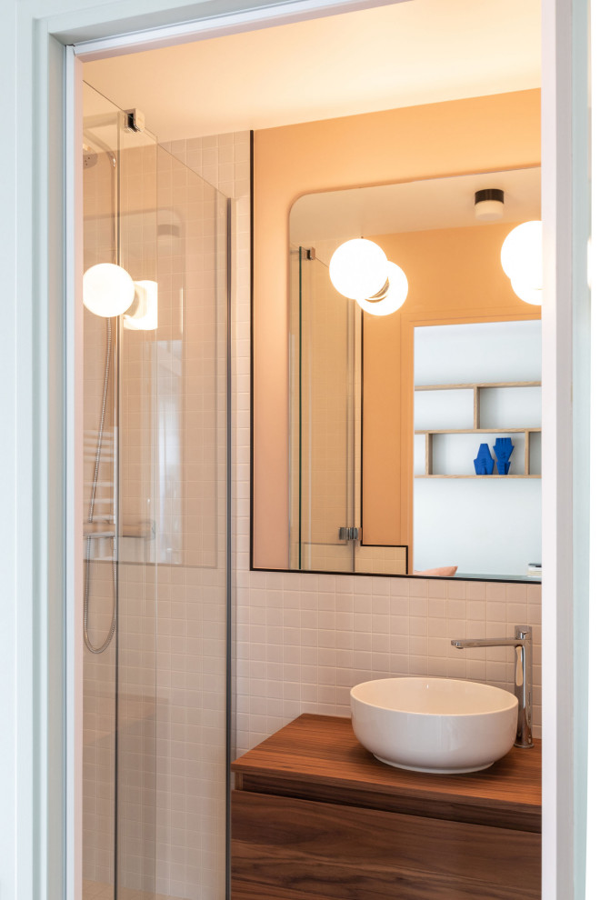 パリにある高級な小さなコンテンポラリースタイルのおしゃれなマスターバスルーム (アルコーブ型シャワー、白いタイル、セラミックタイル、木製洗面台、引戸のシャワー、ニッチ、洗面台1つ、フローティング洗面台、フラットパネル扉のキャビネット、濃色木目調キャビネット、オレンジの壁、ベッセル式洗面器、ブラウンの洗面カウンター) の写真