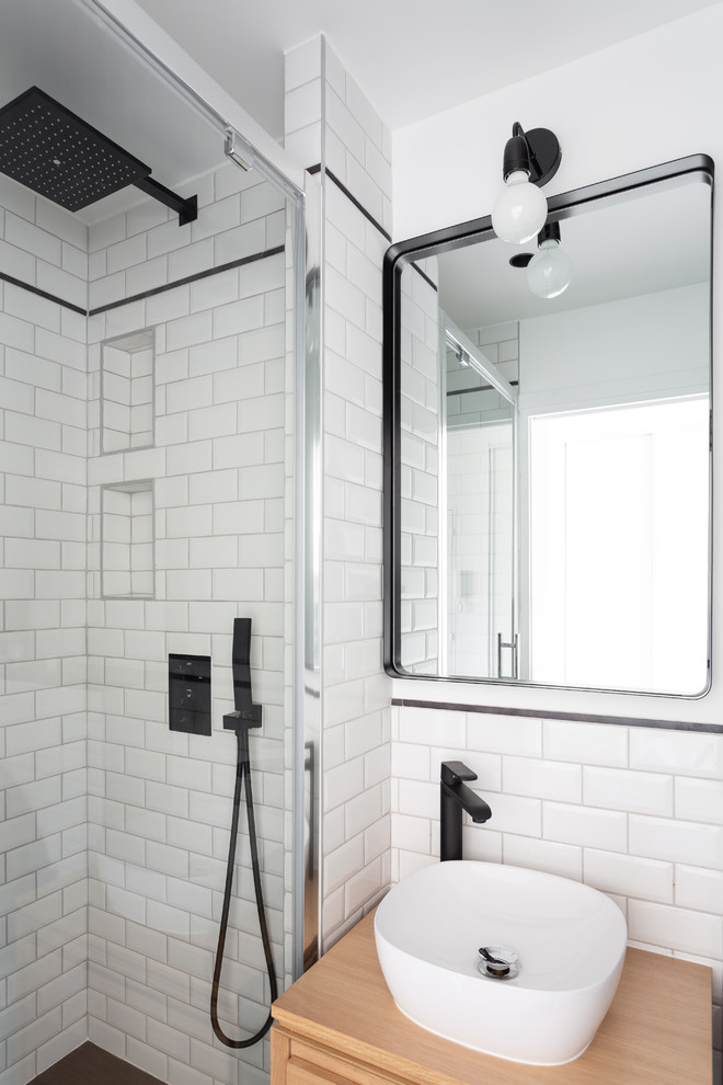 Idéer för ett litet minimalistiskt beige en-suite badrum, med släta luckor, skåp i ljust trä, en kantlös dusch, vit kakel, tunnelbanekakel, vita väggar, klinkergolv i keramik, ett fristående handfat, träbänkskiva, svart golv och dusch med gångjärnsdörr
