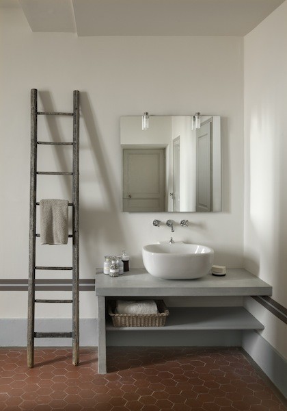 Idée de décoration pour une salle de bain principale champêtre de taille moyenne avec un mur blanc, tomettes au sol, un plan de toilette en béton, une vasque, un placard sans porte et des portes de placard grises.
