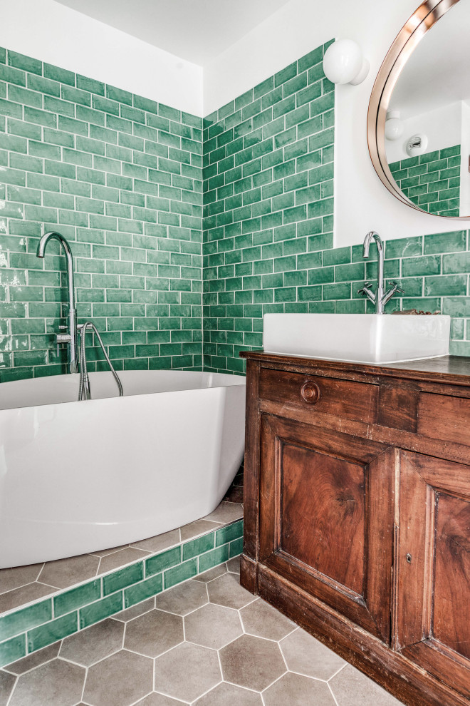 Modelo de cuarto de baño principal clásico renovado de tamaño medio con bañera encastrada, baldosas y/o azulejos verdes, suelo de baldosas de cerámica, lavabo encastrado, encimera de madera y suelo gris