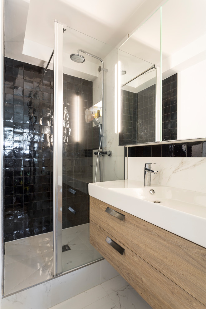 Inspiration for a mid-sized modern master black tile and ceramic tile white floor and marble floor alcove shower remodel in Paris with white walls, flat-panel cabinets, medium tone wood cabinets, a two-piece toilet, a trough sink, solid surface countertops, a hinged shower door and white countertops