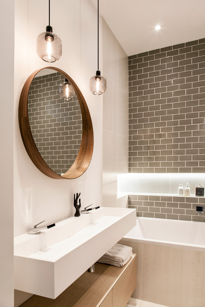 Example of a mid-sized trendy master beige tile and ceramic tile ceramic tile, beige floor and double-sink bathroom design in Paris with flat-panel cabinets, medium tone wood cabinets, a wall-mount toilet, white walls, a trough sink, solid surface countertops, a hinged shower door, white countertops, a niche and a floating vanity