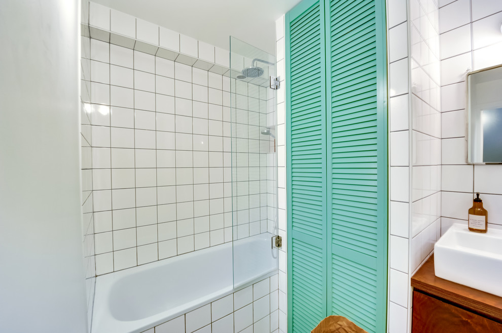 50 tals inredning av ett en-suite badrum, med luckor med lamellpanel, gröna skåp, vit kakel, keramikplattor, vita väggar, målat trägolv, träbänkskiva, ett undermonterat badkar och ett nedsänkt handfat