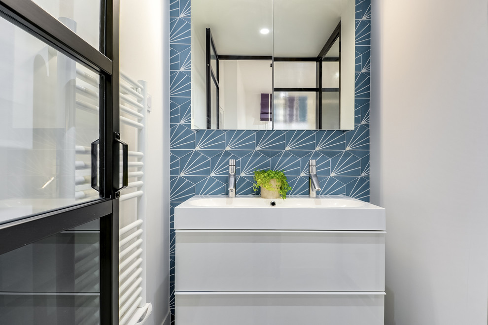 Ispirazione per una stanza da bagno con doccia scandinava di medie dimensioni con ante a filo, ante bianche, piastrelle blu, piastrelle di cemento, pareti bianche, pavimento con piastrelle in ceramica, top in superficie solida e pavimento grigio