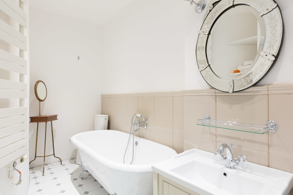 Aménagement d'une salle de bain classique avec une baignoire sur pieds, WC à poser, un mur multicolore et un lavabo posé.