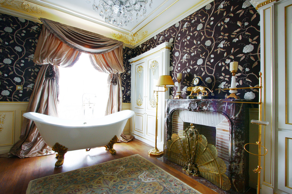 Exemple d'une grande salle de bain principale chic avec une baignoire sur pieds, un mur multicolore et un sol en bois brun.