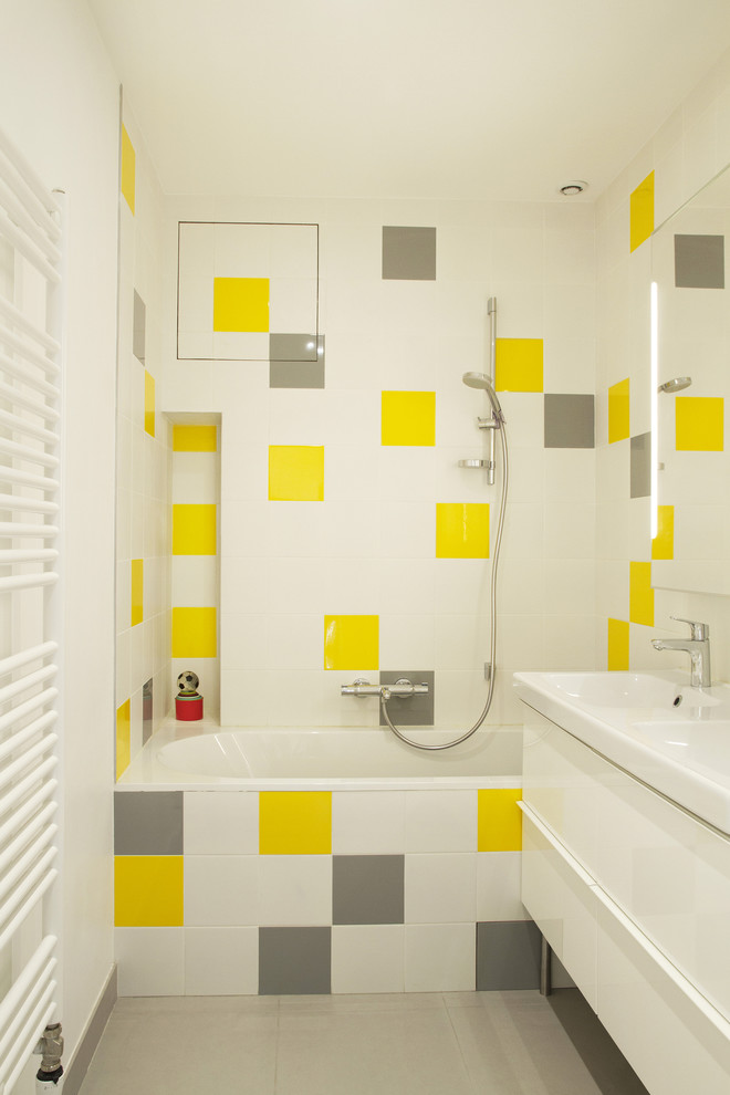 パリにある中くらいなモダンスタイルのおしゃれな子供用バスルーム (オープンシェルフ、アンダーマウント型浴槽、壁掛け式トイレ、黄色いタイル、セラミックタイル、白い壁、セラミックタイルの床、コンソール型シンク) の写真