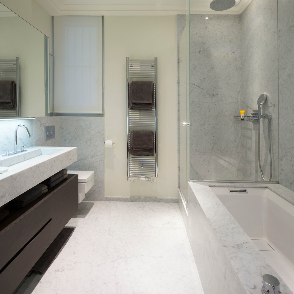 Inredning av ett modernt mellanstort en-suite badrum, med skåp i mörkt trä, ett undermonterat badkar, en hörndusch, en vägghängd toalettstol, vit kakel, grå kakel, vita väggar, marmorgolv, ett integrerad handfat och marmorbänkskiva
