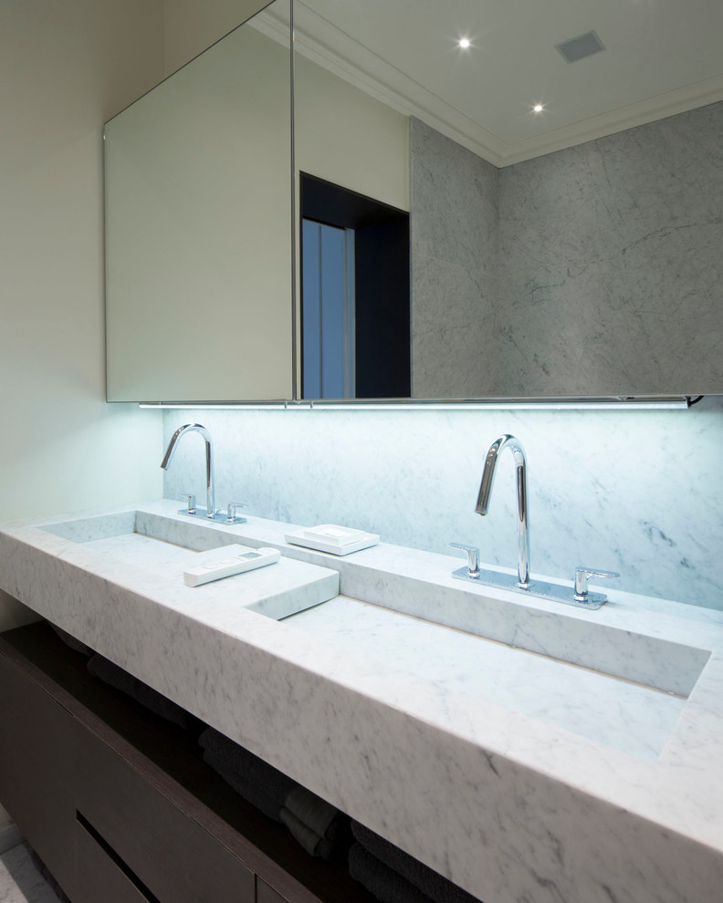 Esempio di una stanza da bagno minimal di medie dimensioni con pareti bianche, lavabo integrato e top in marmo