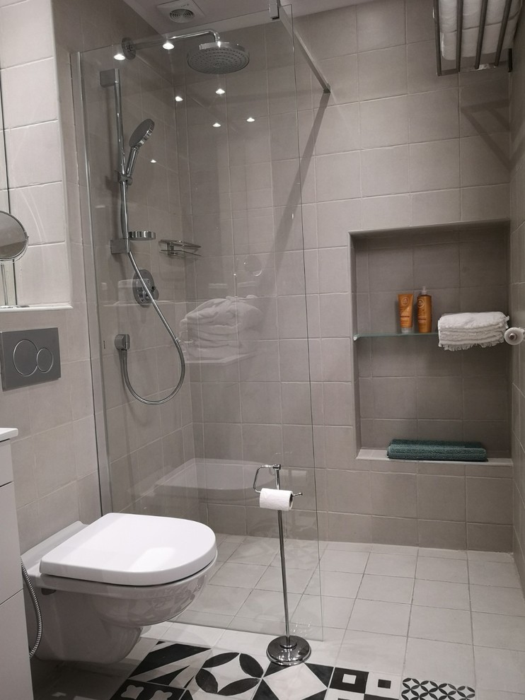 Immagine di una piccola stanza da bagno con doccia design con ante lisce, ante bianche, doccia a filo pavimento, WC sospeso, piastrelle grigie, piastrelle di cemento, pareti grigie, pavimento in cementine, lavabo sottopiano, top piastrellato, pavimento grigio, doccia aperta e top grigio