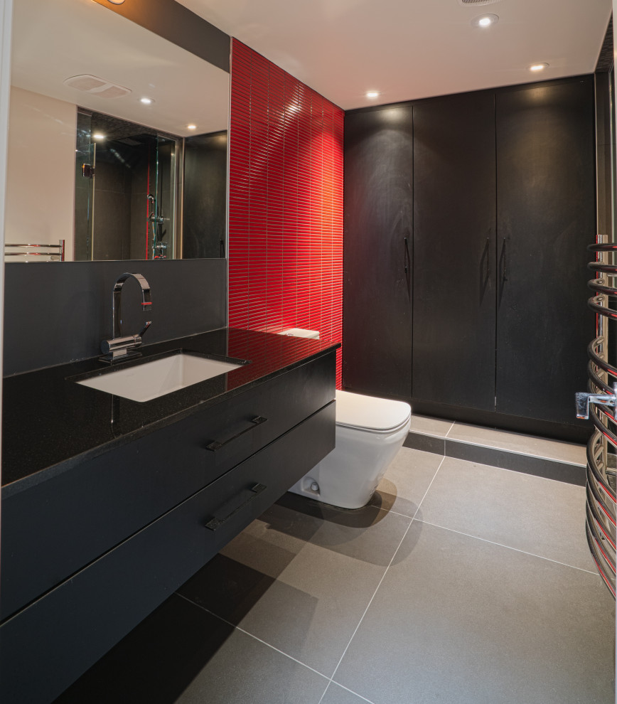 На фото: большая ванная комната в современном стиле с плоскими фасадами, черными фасадами, унитазом-моноблоком, красной плиткой, керамической плиткой, полом из керамогранита, врезной раковиной, серым полом и черной столешницей