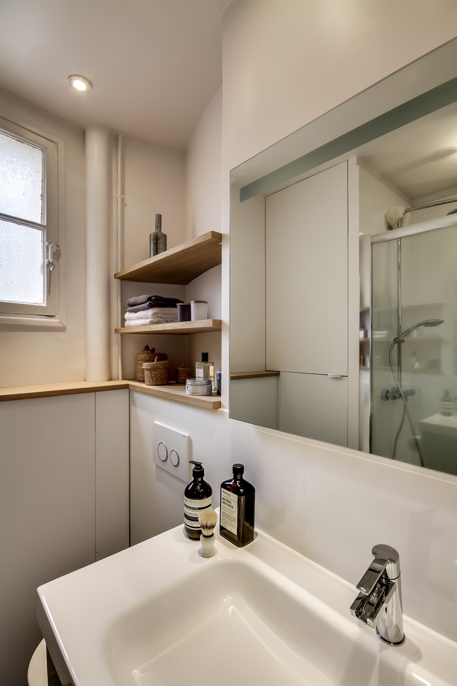Exempel på ett mellanstort minimalistiskt vit vitt badrum med dusch, med släta luckor, grå skåp, en dusch i en alkov, en vägghängd toalettstol, vit kakel, keramikplattor, vita väggar, klinkergolv i keramik, ett konsol handfat, bänkskiva i akrylsten, grått golv och dusch med gångjärnsdörr
