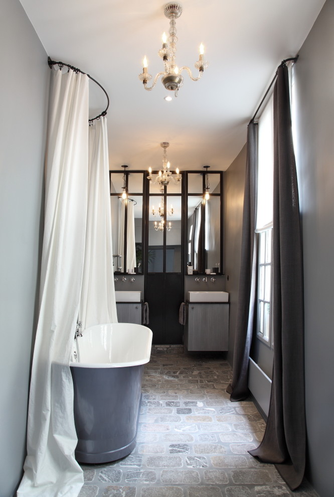 Foto de cuarto de baño principal ecléctico de tamaño medio con bañera exenta, paredes grises, lavabo sobreencimera y suelo de baldosas de terracota
