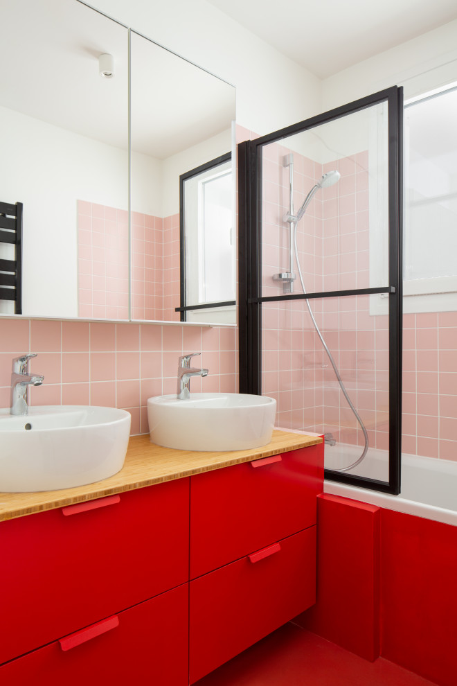 Inredning av ett modernt litet beige beige badrum med dusch, med släta luckor, röda skåp, ett badkar i en alkov, en dusch/badkar-kombination, rosa kakel, vita väggar, ett fristående handfat, träbänkskiva och rött golv