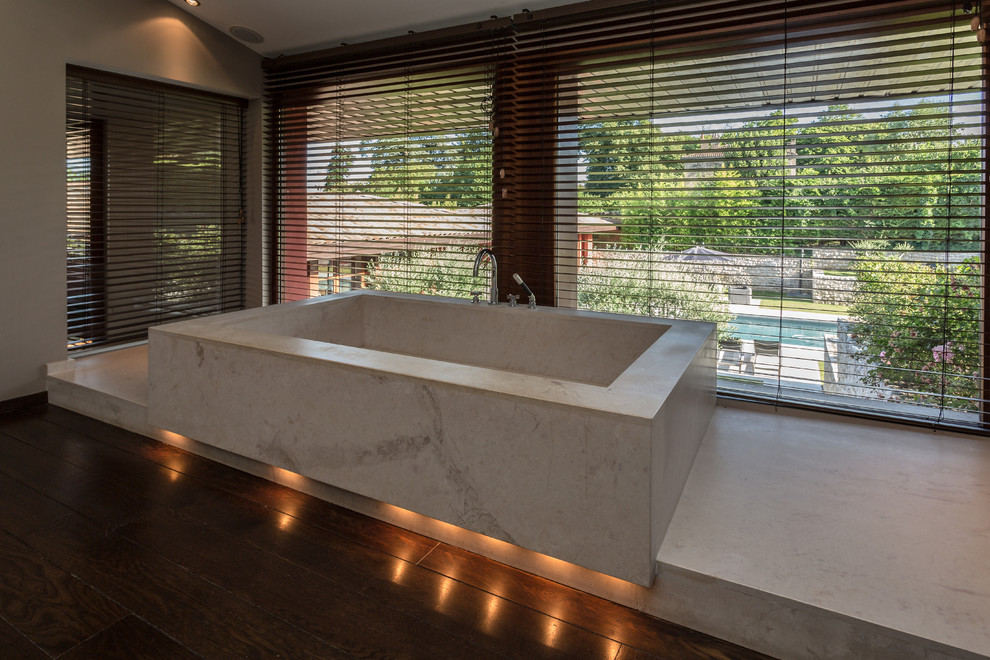 Immagine di una grande stanza da bagno padronale contemporanea con vasca sottopiano, piastrelle beige e parquet scuro