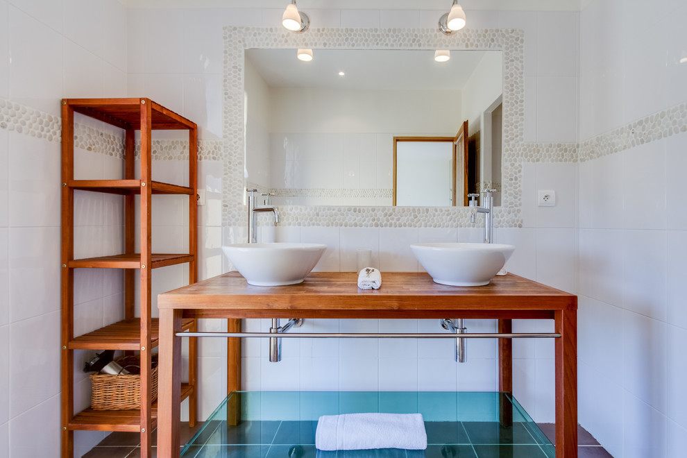 Réalisation d'une salle de bain principale design en bois brun de taille moyenne avec une plaque de galets, un mur blanc, un sol en carrelage de céramique, une vasque, un placard sans porte, un carrelage blanc, un plan de toilette en bois et un plan de toilette marron.