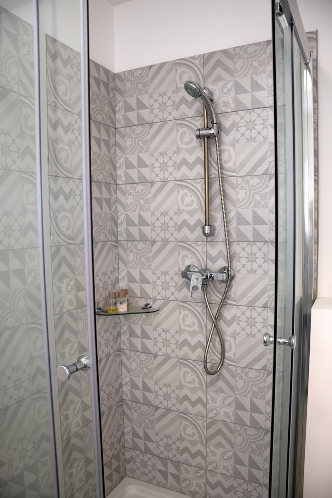 Cette image montre une petite salle d'eau design avec une douche d'angle, WC suspendus, un carrelage gris, des carreaux de céramique, un mur blanc, un sol en vinyl, un plan vasque, un sol marron et une cabine de douche à porte coulissante.