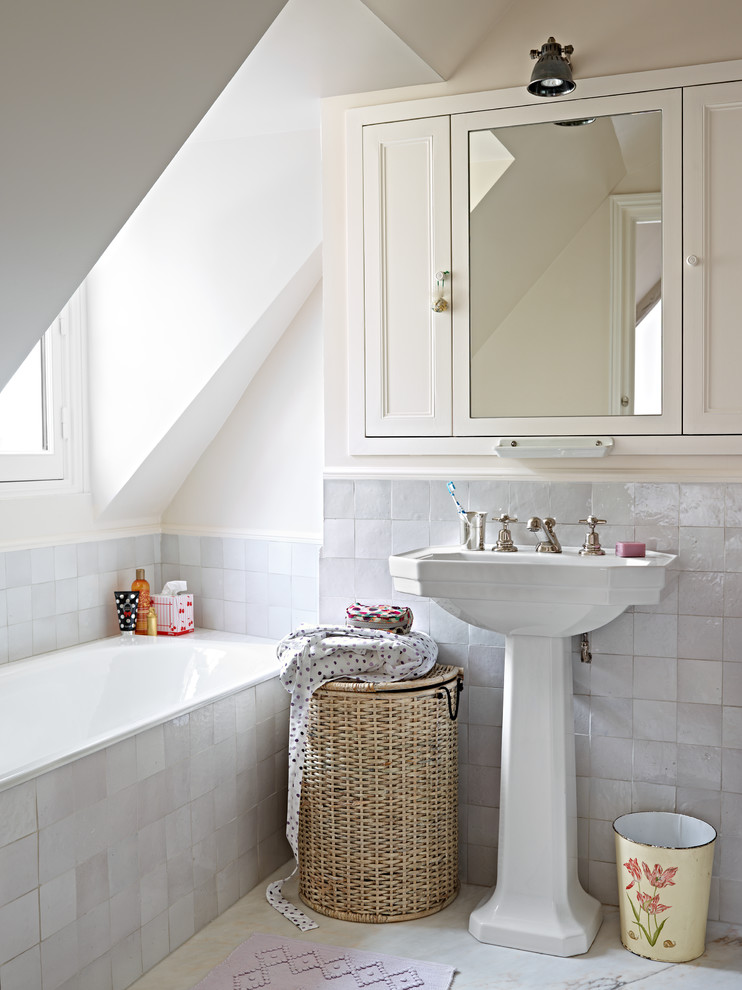 Diseño de cuarto de baño principal tradicional renovado pequeño con lavabo con pedestal, armarios con paneles empotrados, puertas de armario blancas, bañera empotrada, baldosas y/o azulejos grises y paredes blancas