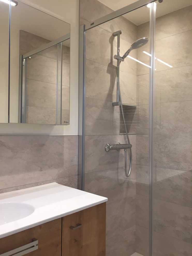 Idéer för att renovera ett litet funkis vit vitt badrum med dusch, med släta luckor, skåp i ljust trä, en kantlös dusch, beige kakel, stenhäll, linoleumgolv, ett konsol handfat och flerfärgat golv