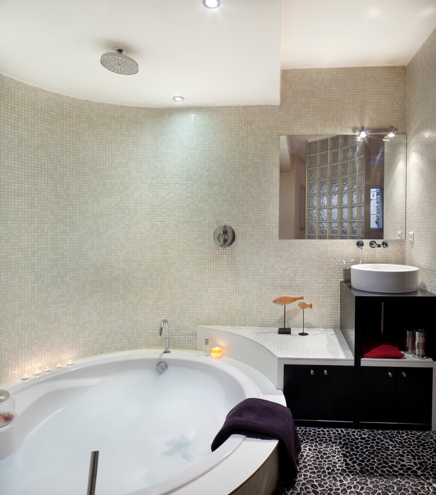 На фото: главная ванная комната среднего размера в современном стиле с настольной раковиной, черными фасадами, душем над ванной, бежевой плиткой, плиткой мозаикой, бежевыми стенами, полом из галечной плитки и гидромассажной ванной