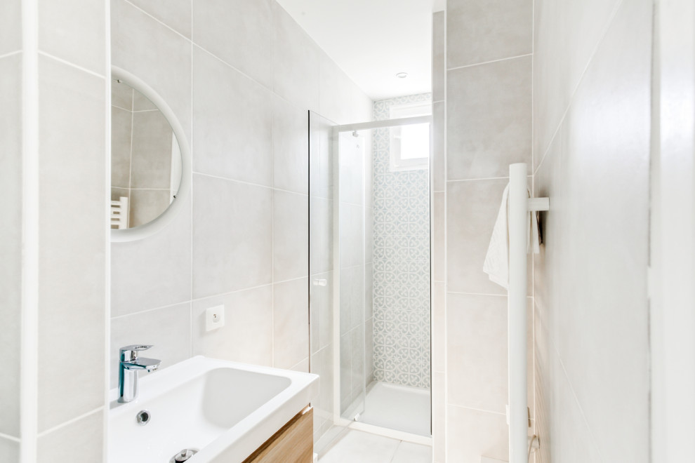 Modern inredning av ett mellanstort vit vitt badrum med dusch, med skåp i ljust trä, en kantlös dusch, en toalettstol med separat cisternkåpa, grå kakel, cementkakel, grå väggar, klinkergolv i terrakotta, ett avlångt handfat, bänkskiva i akrylsten, beiget golv och dusch med gångjärnsdörr