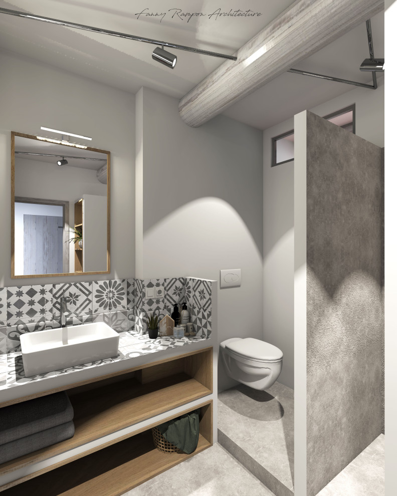 Lantlig inredning av ett litet grå grått en-suite badrum, med skåp i ljust trä, en öppen dusch, en vägghängd toalettstol, grå kakel, keramikplattor, vita väggar, betonggolv, ett nedsänkt handfat, kaklad bänkskiva, grått golv och med dusch som är öppen