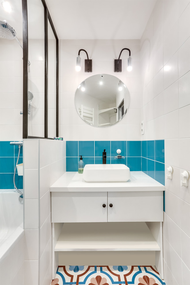Идея дизайна: ванная комната в современном стиле с плоскими фасадами, белыми фасадами, ванной в нише, душем над ванной, синей плиткой, белой плиткой, белыми стенами, душевой кабиной, настольной раковиной, разноцветным полом и открытым душем