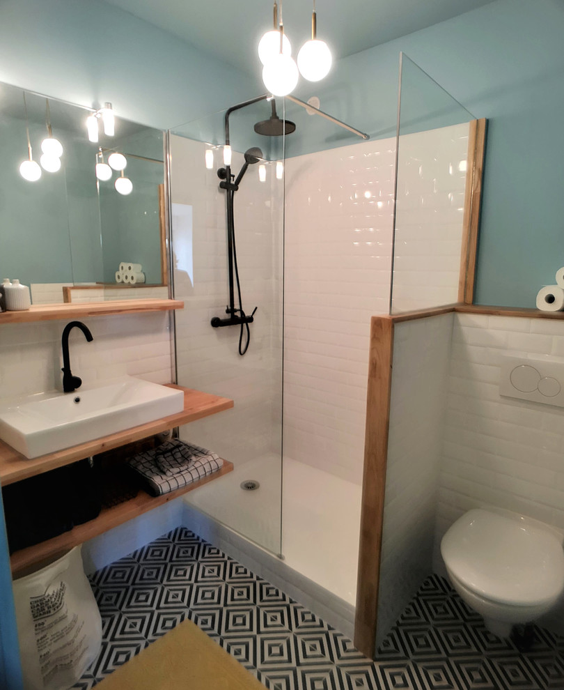 Idée de décoration pour une petite salle d'eau vintage avec WC suspendus, un carrelage blanc, un carrelage métro, un mur bleu, un sol en carrelage de céramique, un lavabo posé, un plan de toilette en bois, un sol multicolore et un plan de toilette orange.