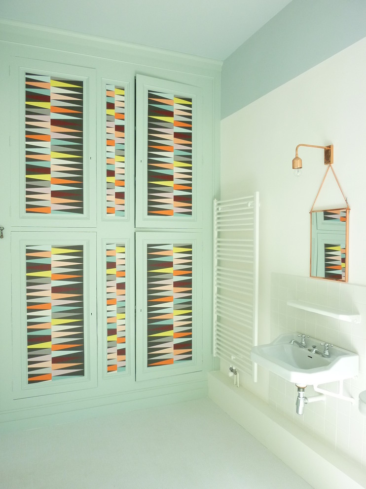 Idée de décoration pour une salle de bain design de taille moyenne avec un lavabo suspendu, des portes de placard bleues, un mur bleu et un carrelage blanc.