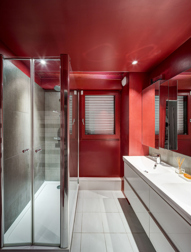 На фото: главная ванная комната среднего размера в современном стиле с плоскими фасадами, белыми фасадами, двойным душем, раздельным унитазом, серой плиткой, керамической плиткой, красными стенами, полом из керамической плитки, подвесной раковиной, белым полом, душем с распашными дверями, белой столешницей, тумбой под две раковины и подвесной тумбой с
