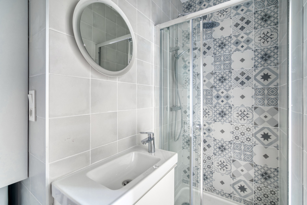 Skandinavisk inredning av ett litet vit vitt badrum med dusch, med luckor med profilerade fronter, skåp i mellenmörkt trä, en dusch i en alkov, en toalettstol med hel cisternkåpa, grå kakel, cementkakel, grå väggar, cementgolv, grått golv och dusch med skjutdörr