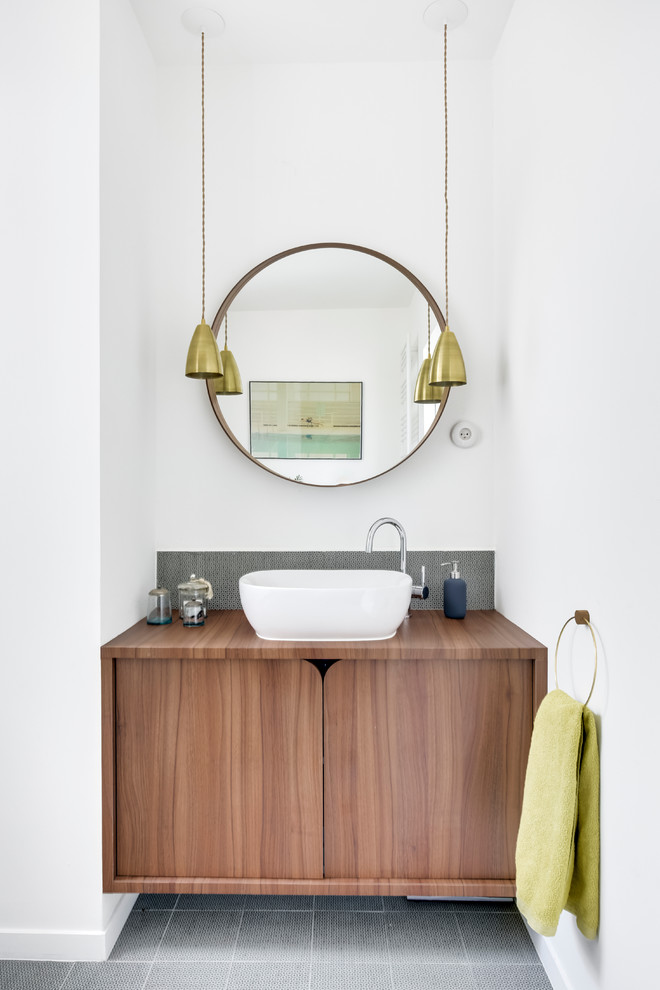 Idées déco pour une salle de bain contemporaine en bois brun avec un placard à porte plane, un mur blanc, une vasque, un plan de toilette en bois, un carrelage blanc, un carrelage gris et carreaux de ciment au sol.